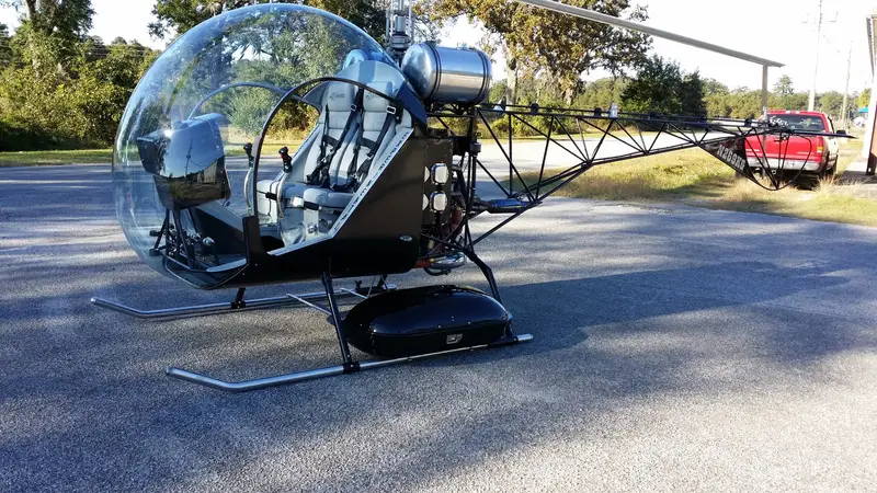 Silver and black Safari 400 helicopter parked on tarmac, side view
