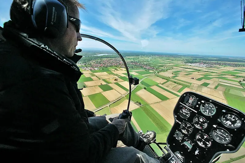 Pilot point of view from a Safari 400 helicopter cockpit flying over farmland