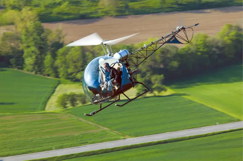 Safari 400 helicopter in flight over green farm fields, seen from the air