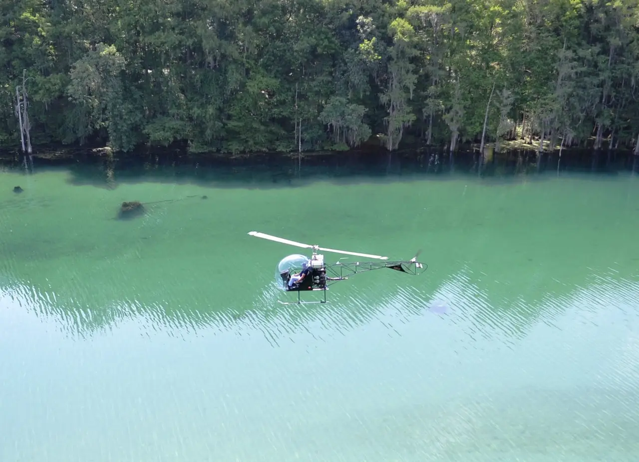 Safari 400 helicopter flying low over turquoise water