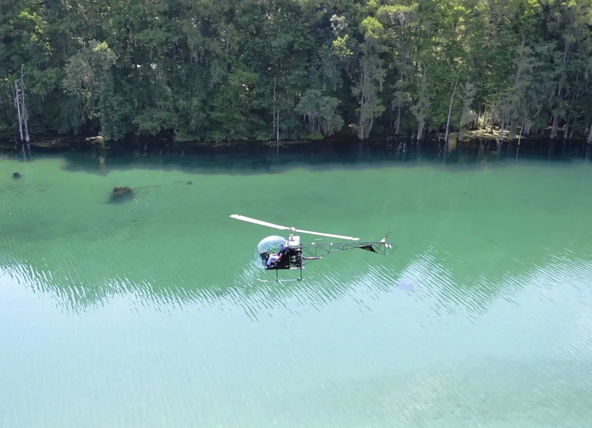 Safari 400 helicopter flying low over turquoise water