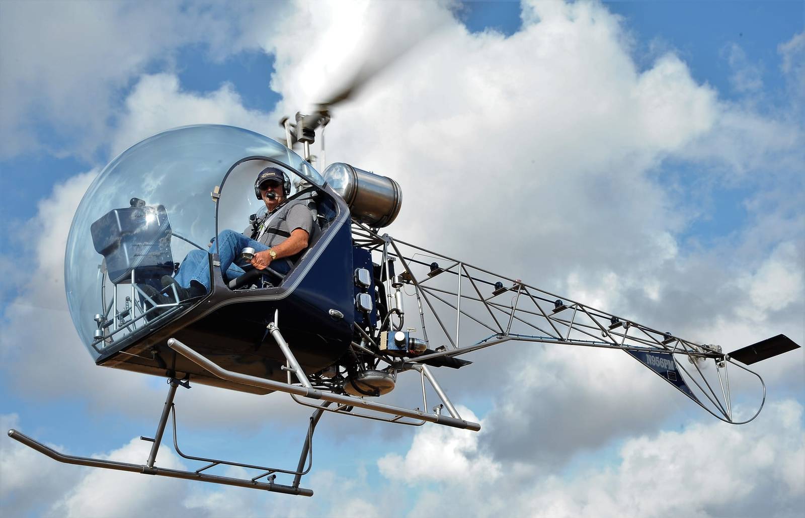 Dark blue Safari 400 helicopter hovering against dramatic storm clouds