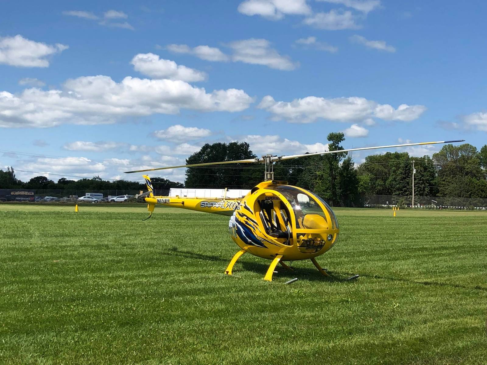 Yellow Safari 500 helicopter parked on grass at a fly-in, side view
