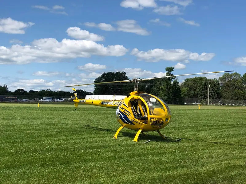 Yellow Safari 500 helicopter parked on grass at a fly-in, side view