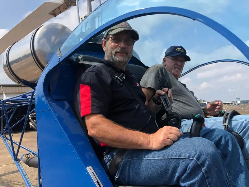 Two people seated in the cockpit of a blue Safari 400 helicopter