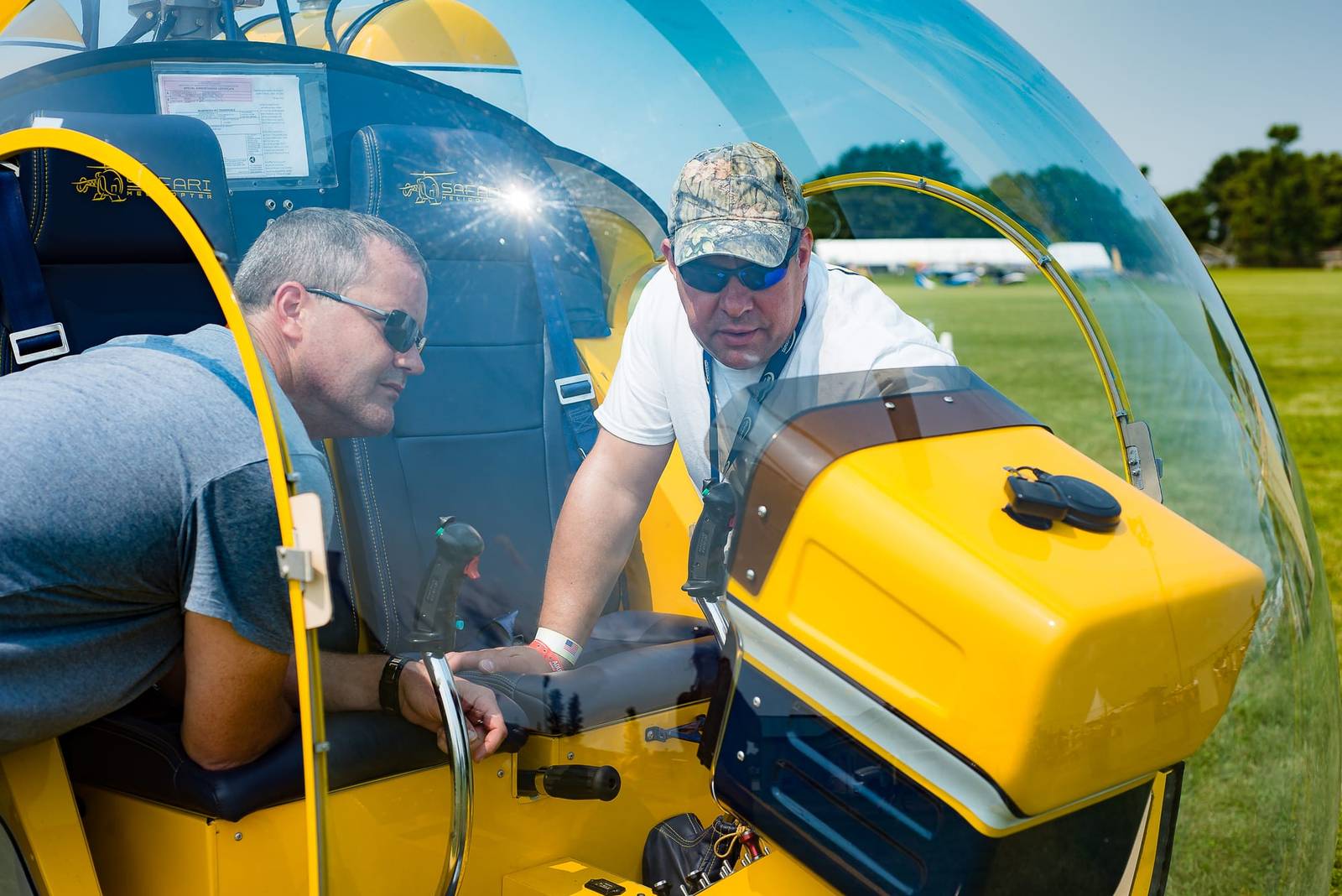 Two people beside the yellow enclosed cabin of a Safari 500 helicopter, close-up