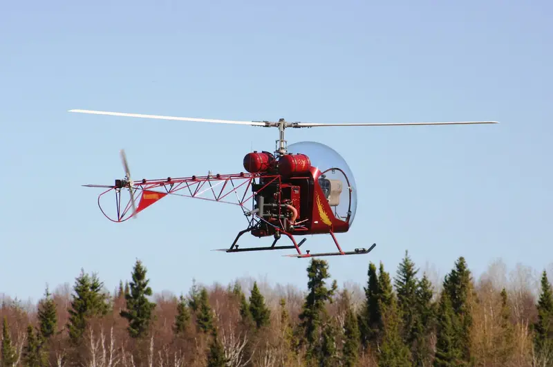 Red Safari 400 helicopter flying over a line of trees